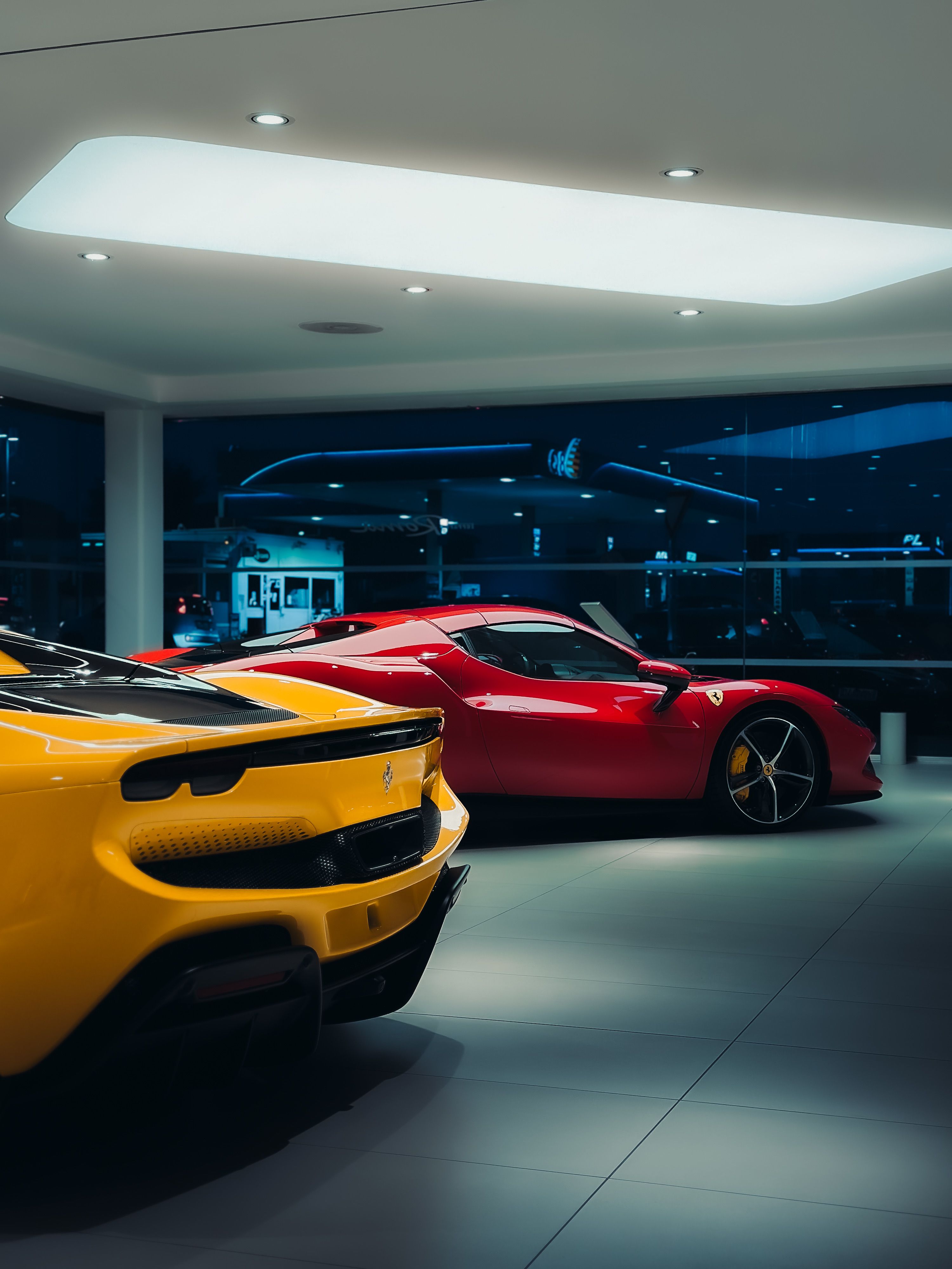 Red and yellow sports cars displayed inside a luxury dealership